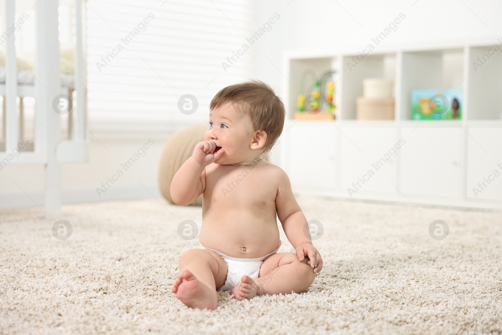 Photo of Cute baby boy sitting on carpet at home