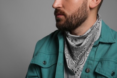 Fashionable young man in stylish outfit with bandana on grey background, closeup