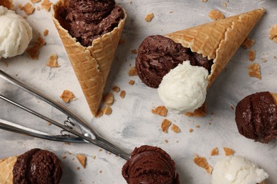 Composition with tasty ice cream scoops in waffle cones on light textured table, above view