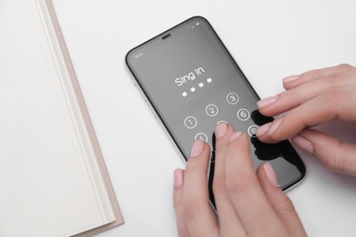 Woman unlocking smartphone with blocked screen at white table, closeup