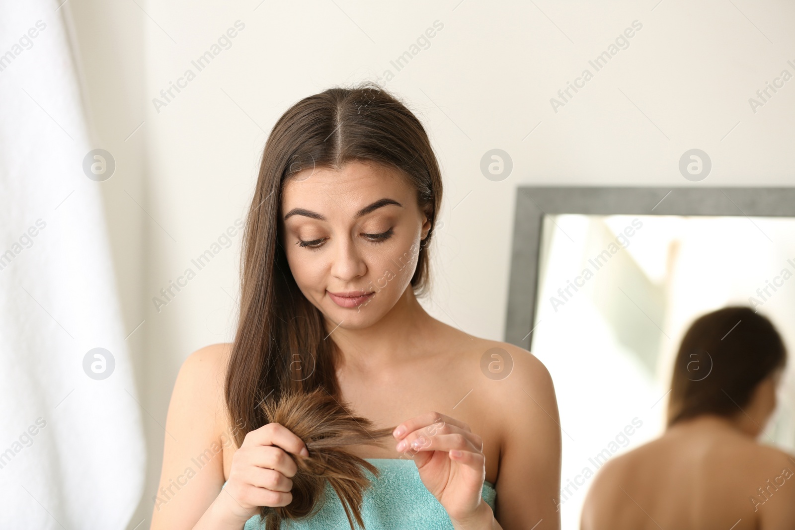 Photo of Emotional woman with damaged hair indoors. Split ends
