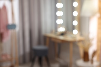 Photo of Blurred view of makeup room with stylish mirror, dressing table and chair