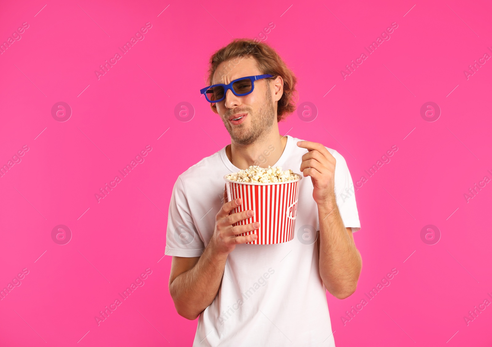 Photo of Emotional man with 3D glasses and popcorn during cinema show on color background