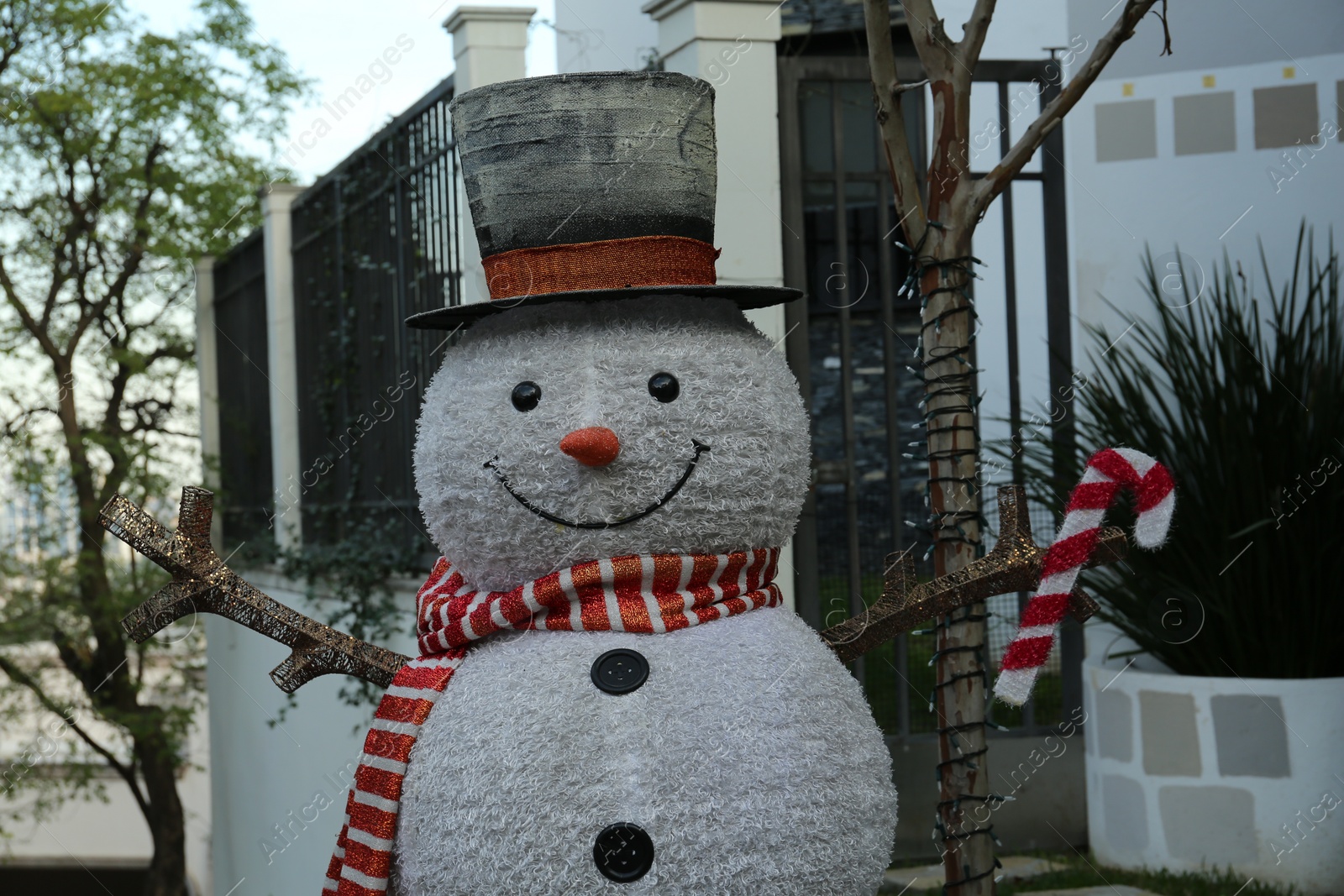 Photo of Funny snowman near house. Festive outdoor Christmas decoration