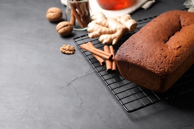 Delicious gingerbread cake and ingredients on black table, space for text