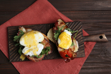 Photo of Delicious eggs Benedict served on wooden table, flat lay