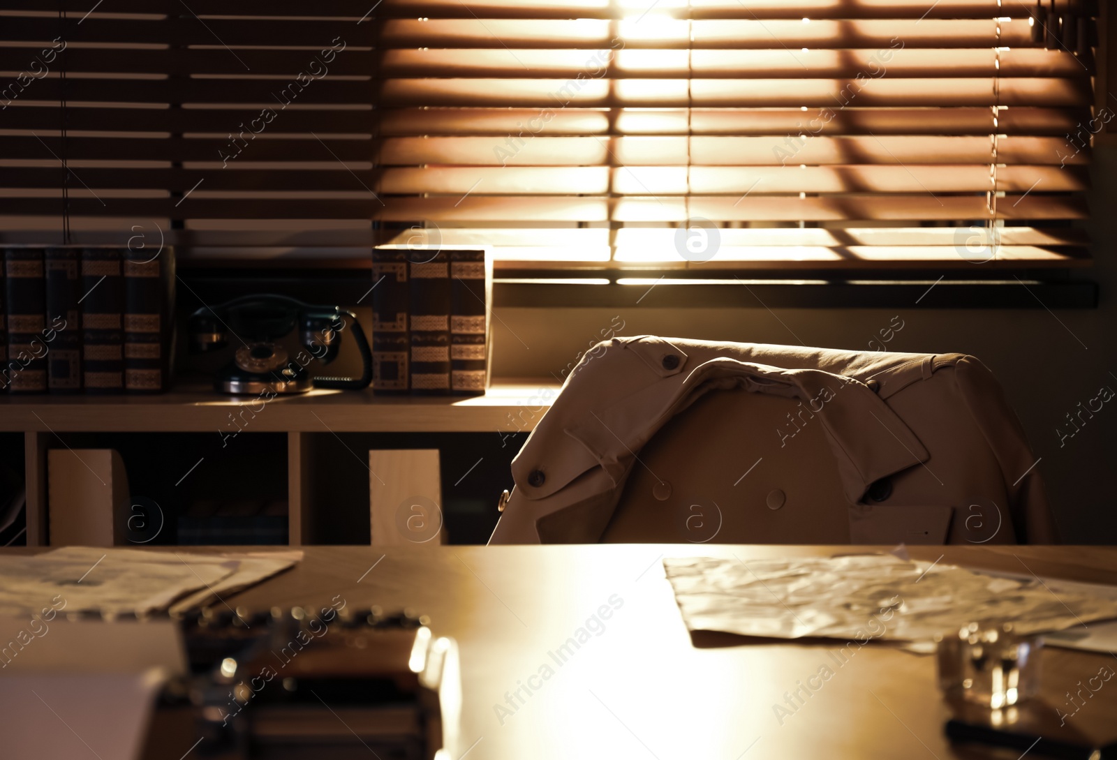 Photo of Grey coat on chair near wooden table in detective office