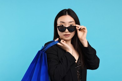 Photo of Beautiful woman with shopping bags on light blue background