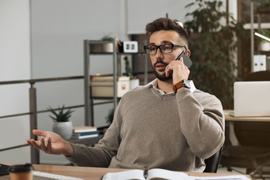 Man talking on phone while working at table in office