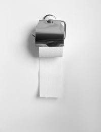 Photo of Toilet paper holder with roll on light wall