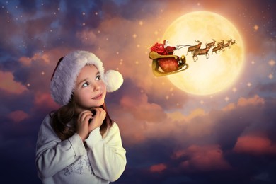 Cute little child and Santa Claus flying in his sleigh on background. Christmas celebration