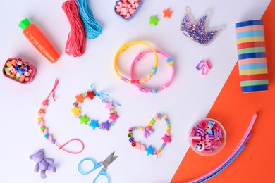 Photo of Kid's handmade beaded jewelry and different supplies on color background, flat lay