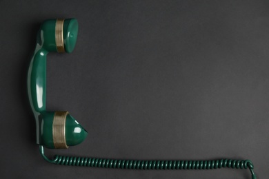 Photo of Handset of vintage green telephone on black background, top view. Space for text