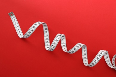 White measuring tape on red background, top view