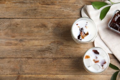 Photo of Glasses of milk with delicious grass jelly on wooden table, flat lay. Space for text