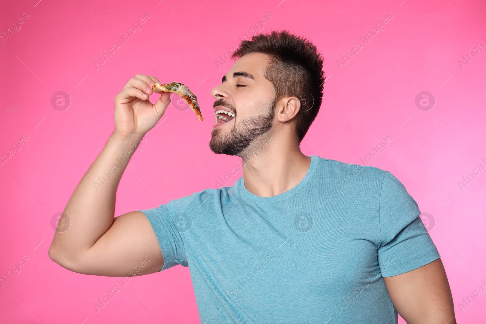 Photo of Handsome man eating pizza on pink background