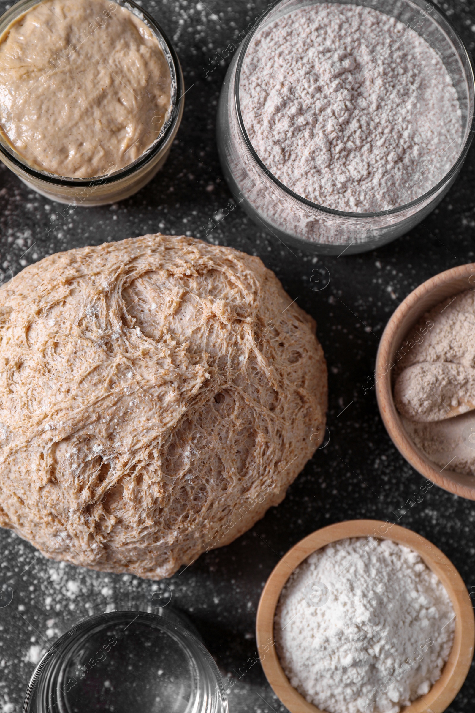 Photo of Fresh sourdough, flour and water on grey table, flat lay