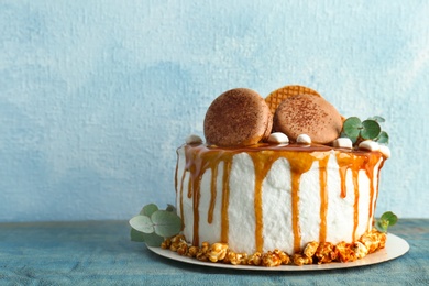 Photo of Delicious homemade cake with caramel sauce and popcorn on table