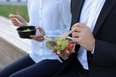 Photo of Business people eating from lunch boxes outdoors, closeup