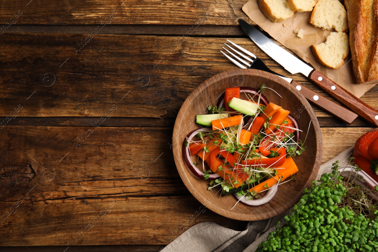 Photo of Salad with fresh organic microgreen in bowl on wooden table, flat lay. Space for text