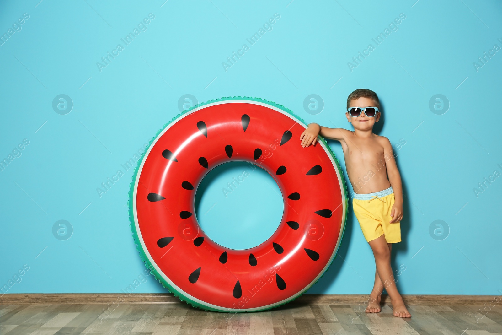 Photo of Cute little boy with inflatable ring near color wall