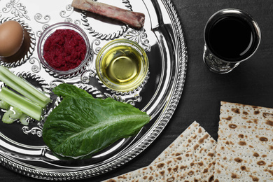Photo of Flat lay composition with Passover Seder plate (keara) on black table. Pesah celebration