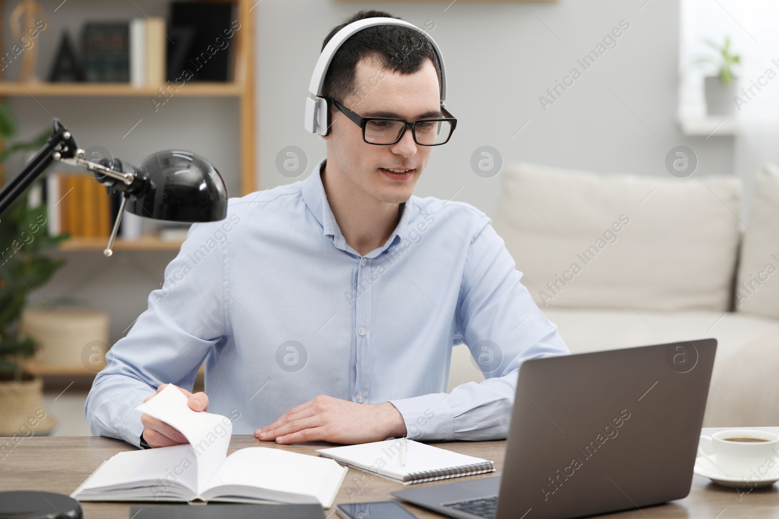 Photo of E-learning. Young man using laptop during online lesson at table indoors.