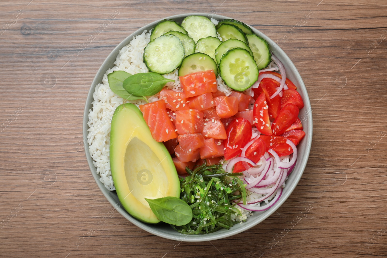 Photo of Delicious poke bowl with salmon and vegetables on wooden table, top view