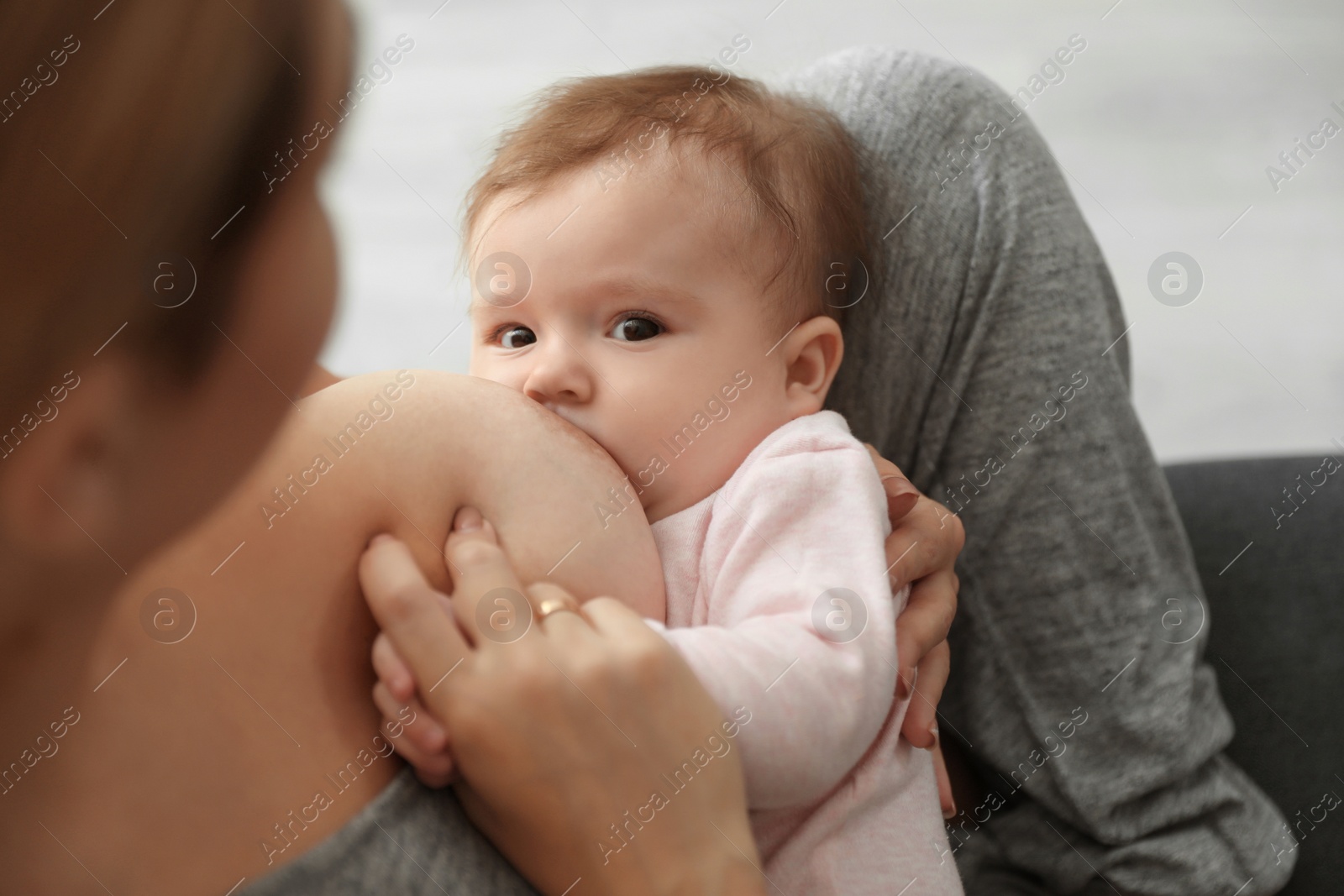 Photo of Young woman breastfeeding her baby at home, closeup