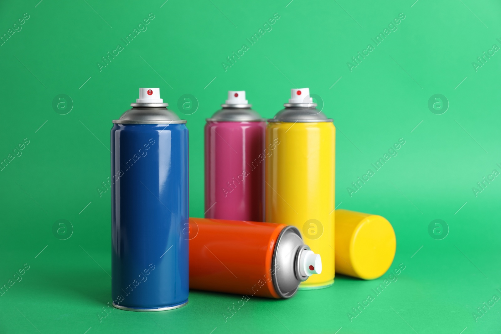 Photo of Colorful cans of spray paints on green background