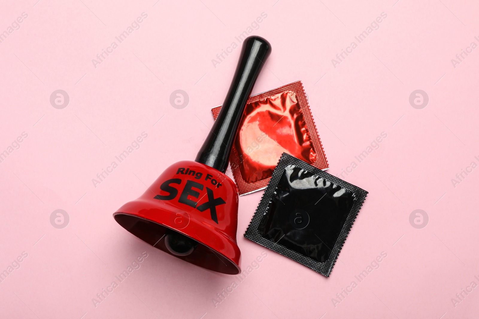 Photo of Sex bell and condoms on pink background, top view