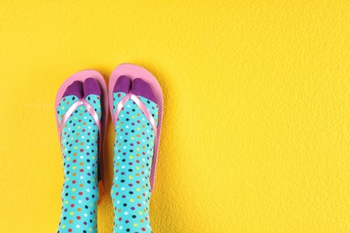 Photo of Woman wearing bright socks with flip-flops and space for design on color background