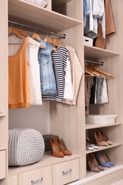 Stylish clothes and shoes in large wardrobe closet