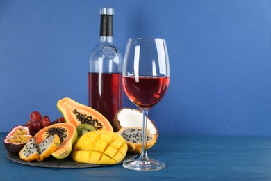 Photo of Delicious exotic fruits and wine on blue wooden table