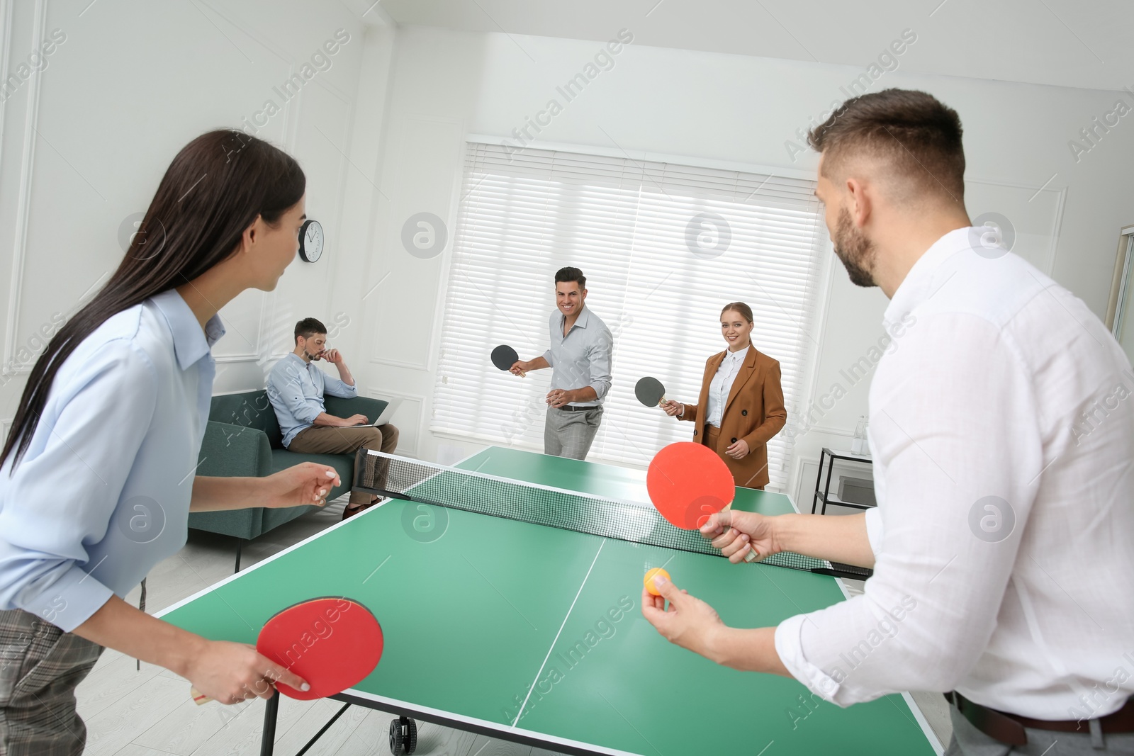 Photo of Business people playing ping pong in office