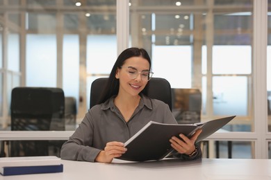 Smiling woman working at table in office. Lawyer, businesswoman, accountant or manager