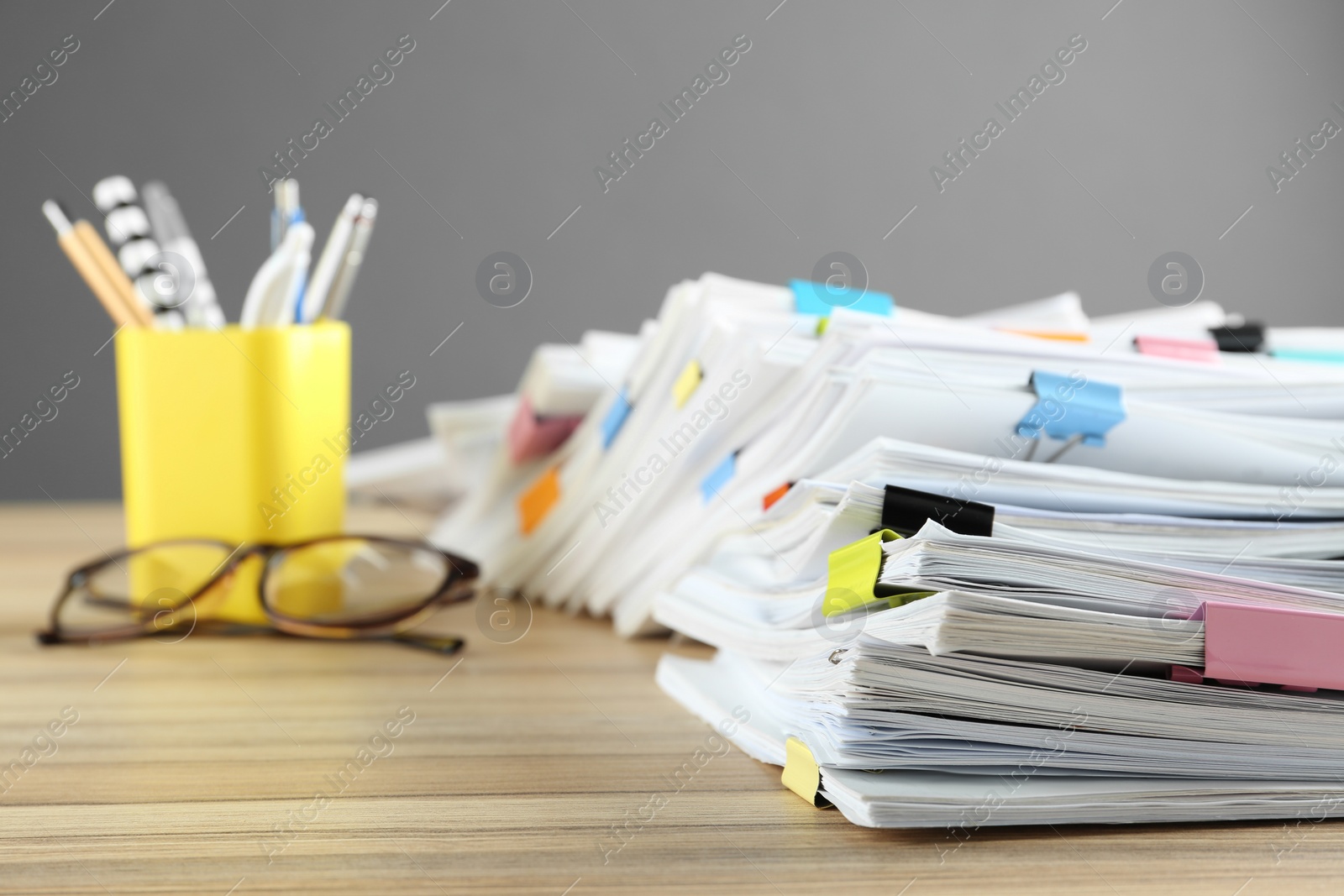 Photo of Stack of documents with binder clips and glasses on wooden table