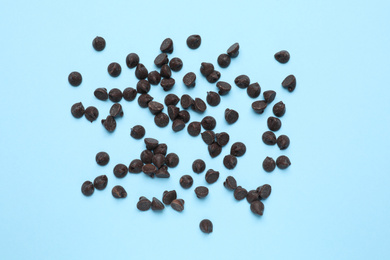 Photo of Delicious dark chocolate chips on light blue background, top view