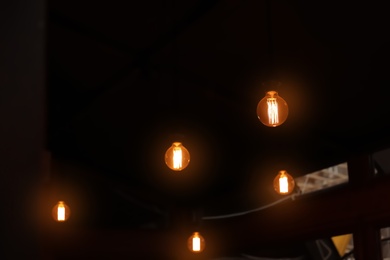 Glowing lamp bulbs in dark room. Space for text