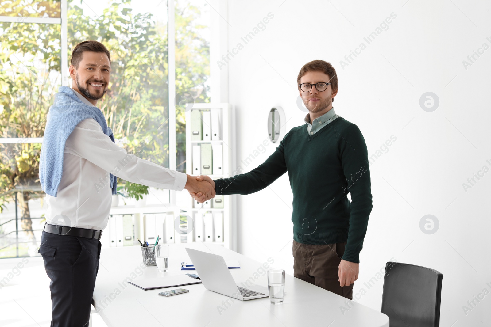 Photo of Human resources manager shaking hands with applicant during job interview in office