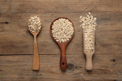 Photo of Scoop and spoons with oatmeal on wooden table, flat lay