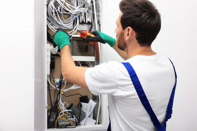 Electrician cutting wires in fuse box indoors