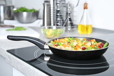 Photo of Frying pan with frozen vegetables on electric stove