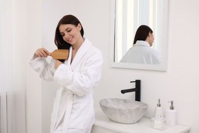Beautiful woman brushing her hair in bathroom