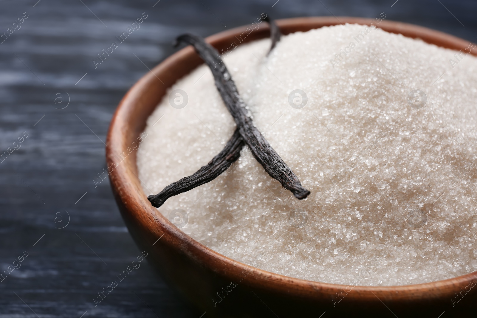 Photo of Bowl with vanilla sugar and sticks on wooden background