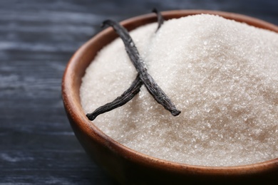 Photo of Bowl with vanilla sugar and sticks on wooden background