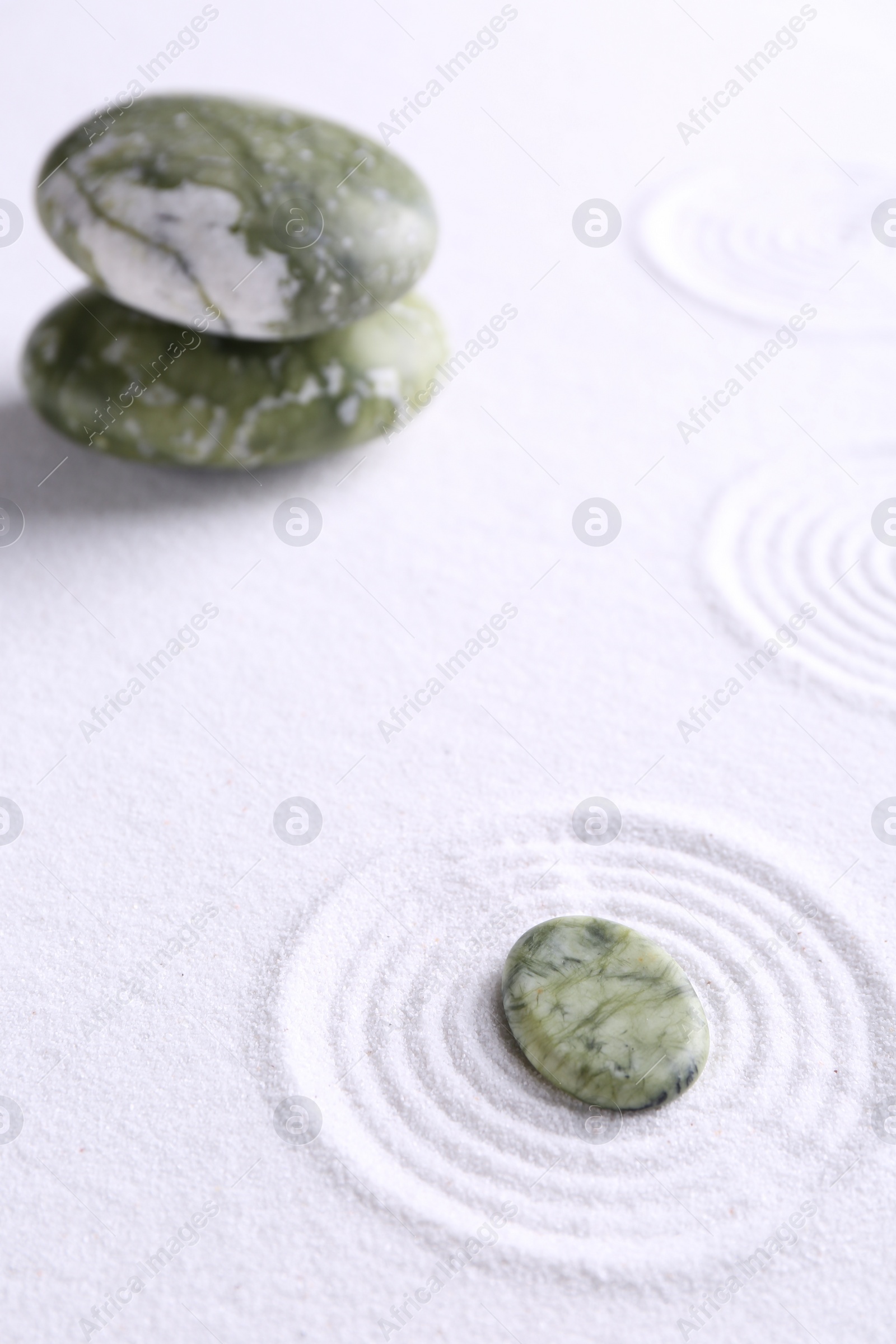 Photo of Zen garden stones on white sand with pattern