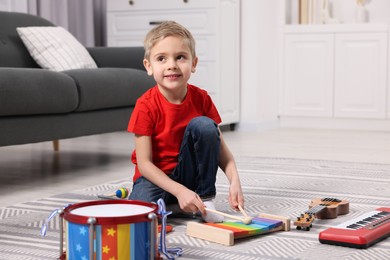 Photo of Little boy playing toy xylophone at home