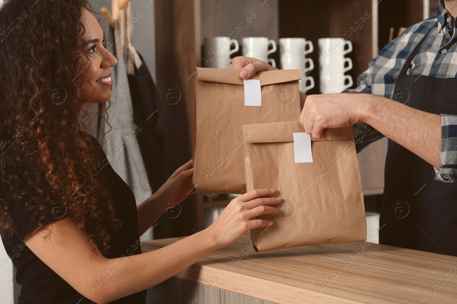 Photo of Worker giving paper bags to customer in cafe