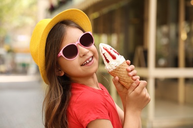 Cute little girl with delicious ice cream in park